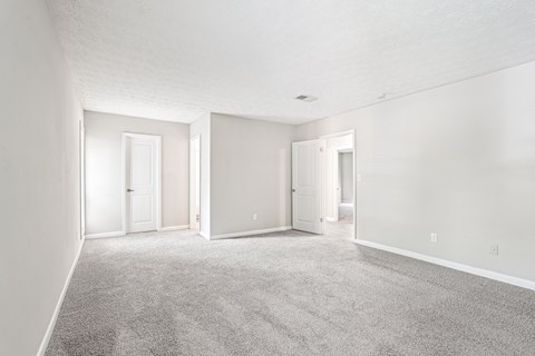 A spacious room with carpeted floor and three doors.