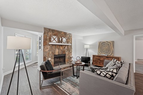 A living room with a grey couch and a stone fireplace.
