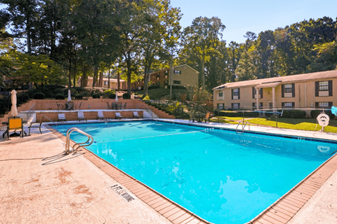 A large swimming pool surrounded by trees and apartment buildings.