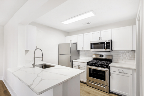 A kitchen with white cabinets and a marble countertop.