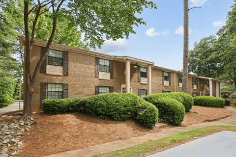 Apartment building with green trees and bushes in front.