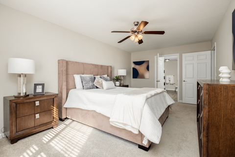A bedroom with a large bed and a ceiling fan.