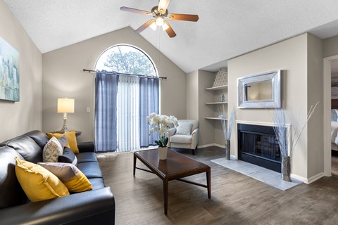 A living room with a black leather couch and a fireplace.