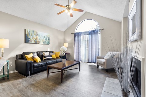 A living room with a black couch and a painting on the wall.