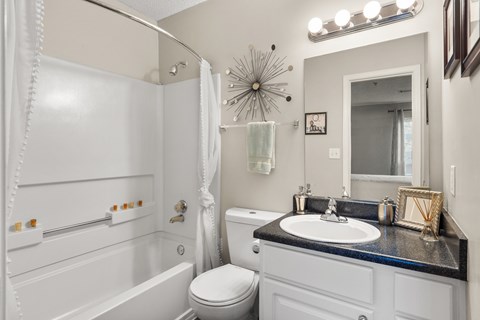 A white bathroom with a black counter top and a white toilet.