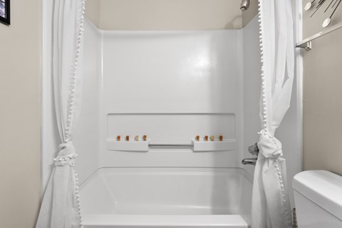 A white bathroom with a tub and toilet.
