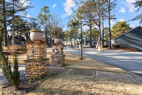 A street view with two stone pillars and a yellow post.