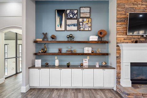 A living room with a fireplace and a shelf with decorative items.