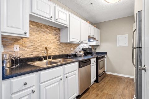 A kitchen with white cabinets and a brick backsplash.