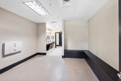A hallway with a white wall and a black door.
