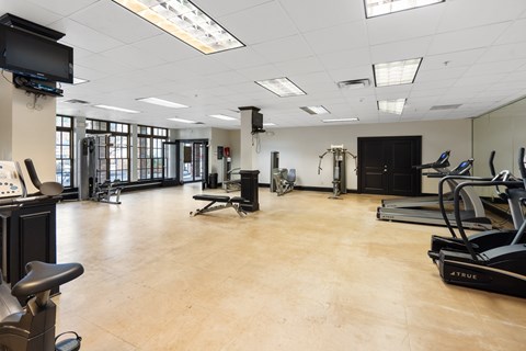 A gym with a variety of exercise equipment including treadmills and weights.
