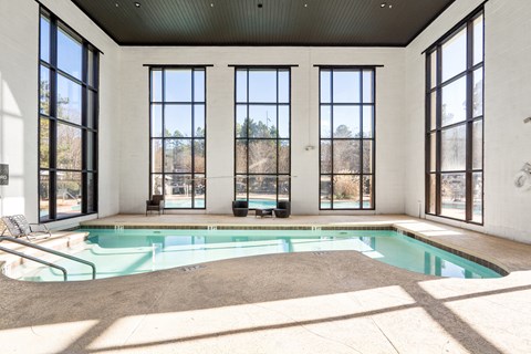 A large indoor swimming pool with a sunny day outside.