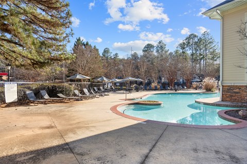 A large outdoor swimming pool surrounded by trees and a gazebo.