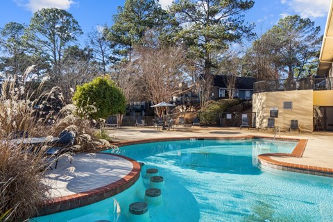A swimming pool surrounded by a brick border and a wooden deck.