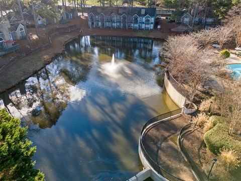 A fountain in the middle of a pond surrounded by a brick wall.