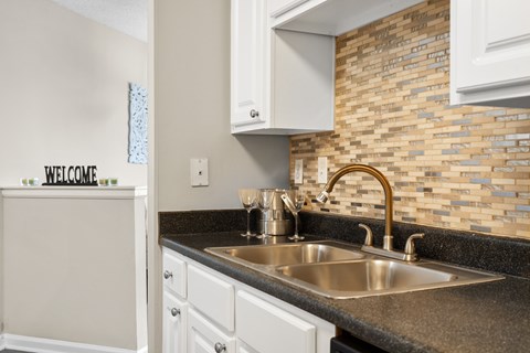 A kitchen with a sink and a wall with a brick pattern.