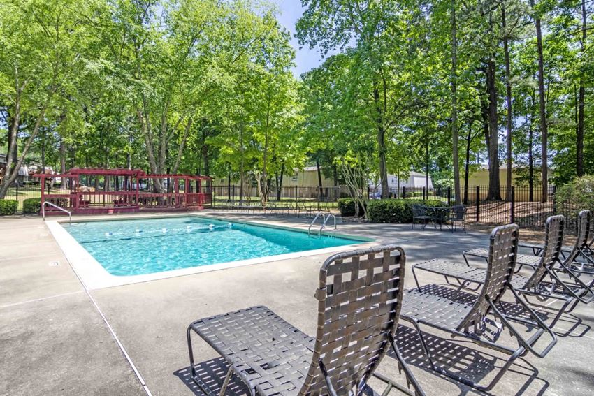our resort style swimming pool is surrounded by chairs and trees