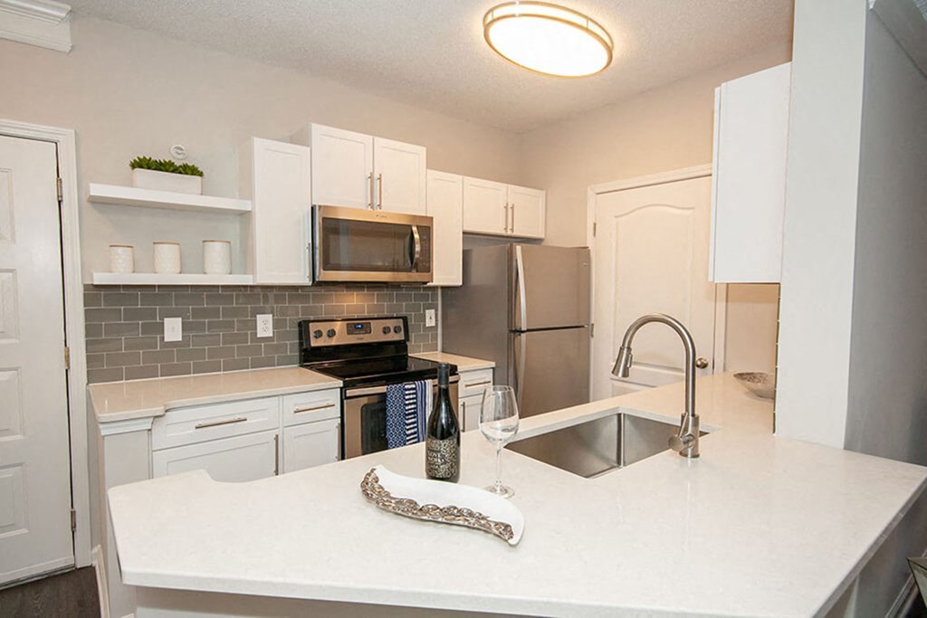 A kitchen with a white counter top and stainless steel appliances.
