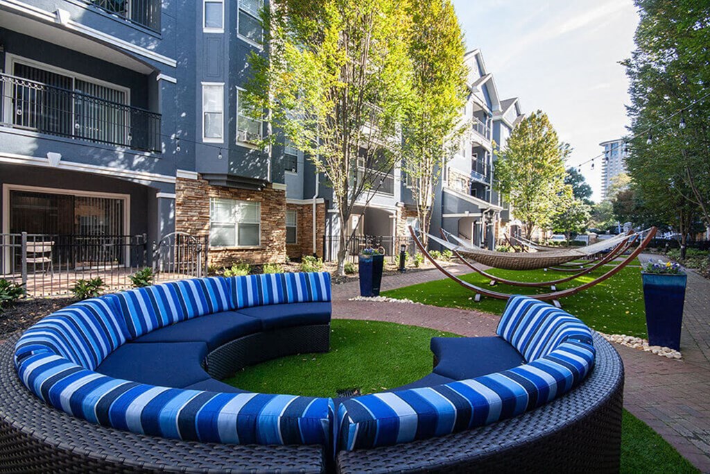A blue and white striped couch sits in the middle of a grassy area.