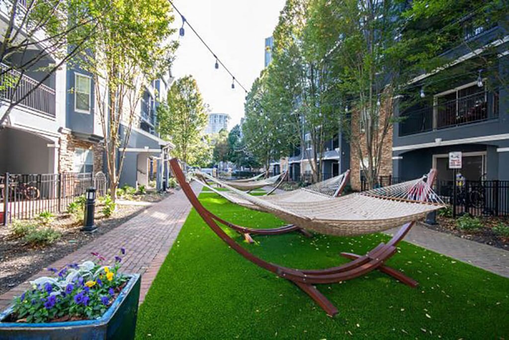 A hammock is strung between two trees in a grassy area.