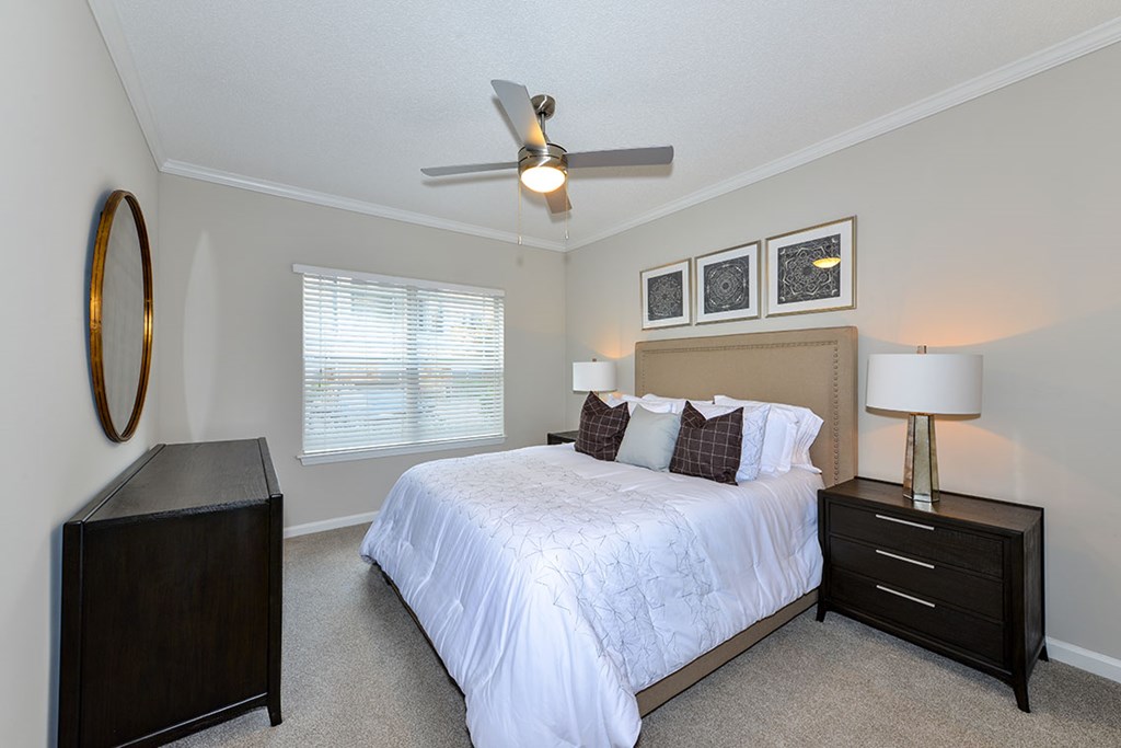 A bedroom with a bed, nightstand, and a ceiling fan.
