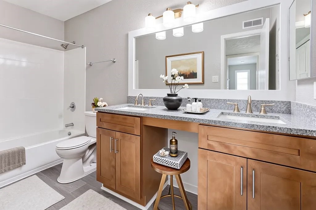 A bathroom with a white toilet, a wooden cabinet, and a large mirror.