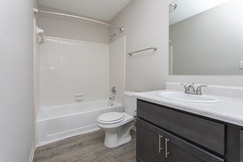 A white toilet sits in a bathroom next to a white sink.