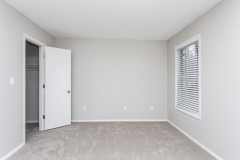 A room with a door and a window with blinds.