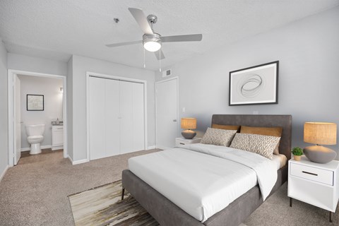 a bedroom with a white bed and a ceiling fan