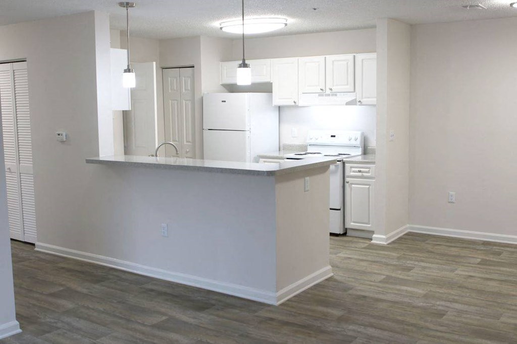 an empty kitchen with white cabinets and a counter top