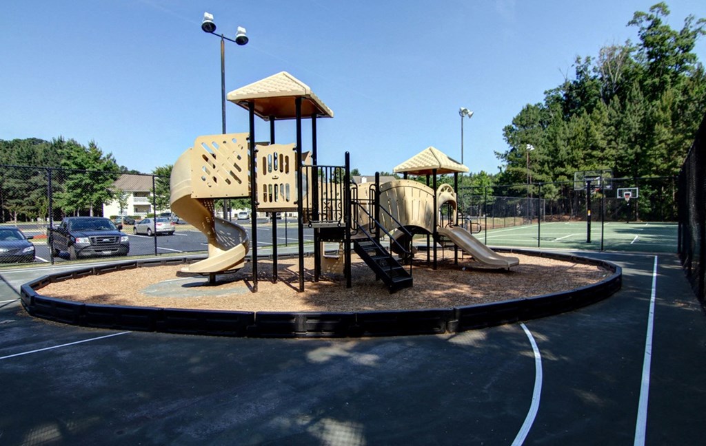 a playground with two slides on a roundabout in a parking lot