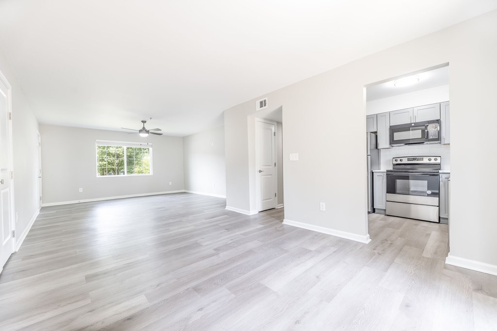 A spacious room with a kitchen area in the background.