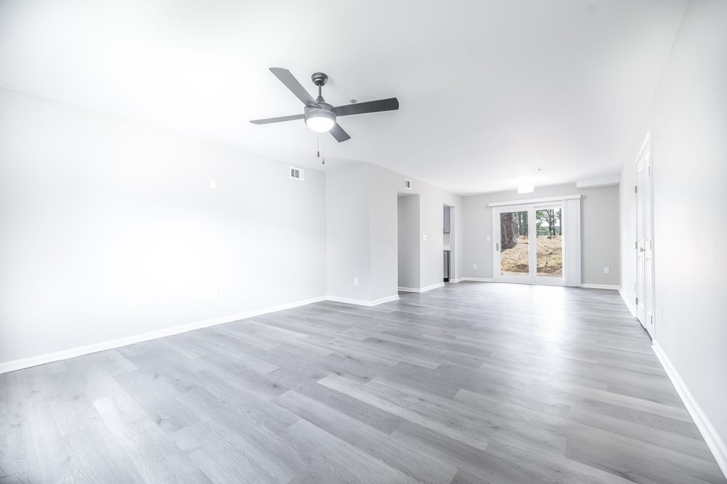 A room with a ceiling fan and light, and a door leading to a balcony.