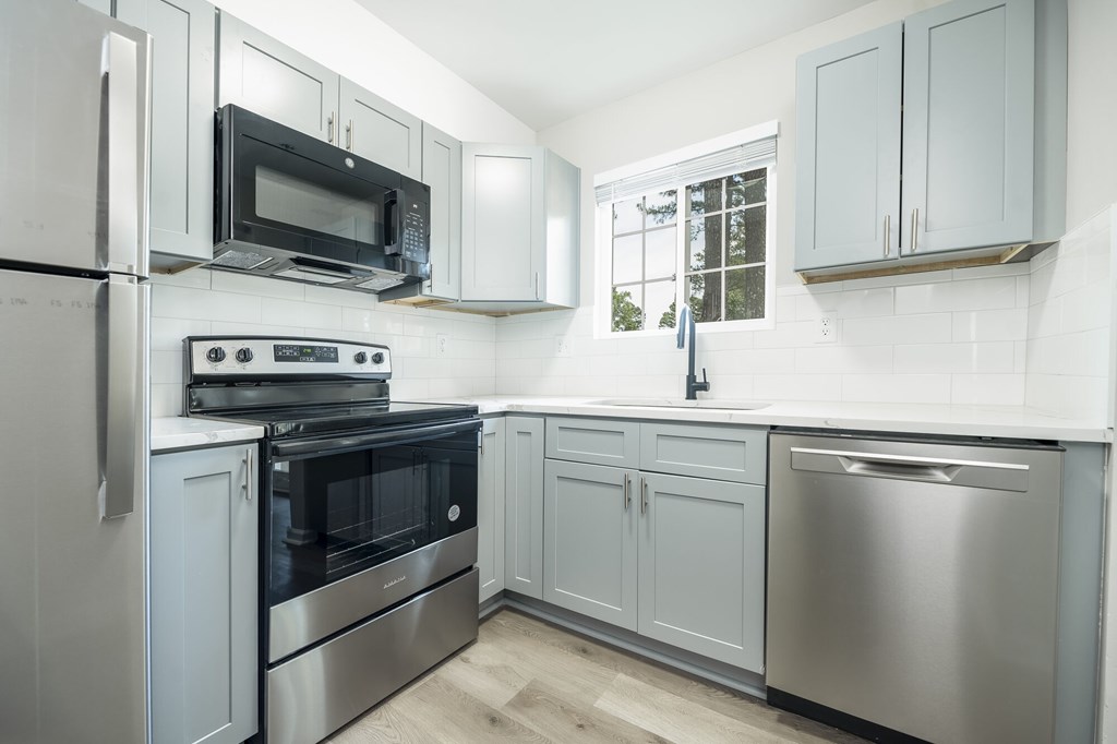 A kitchen with a stainless steel refrigerator, oven, and microwave.