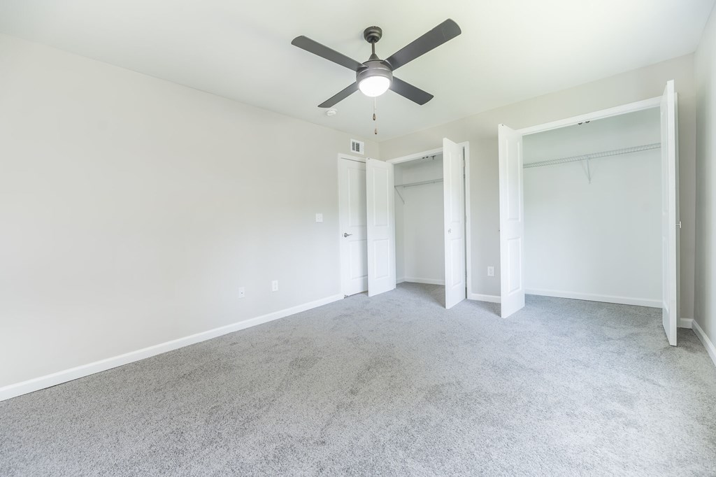 A room with a ceiling fan and carpeted floor.