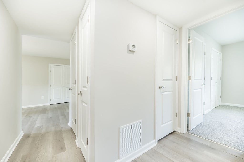 A hallway with white walls and wood flooring.