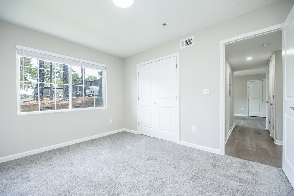 A spacious room with a large window and carpeted floor.