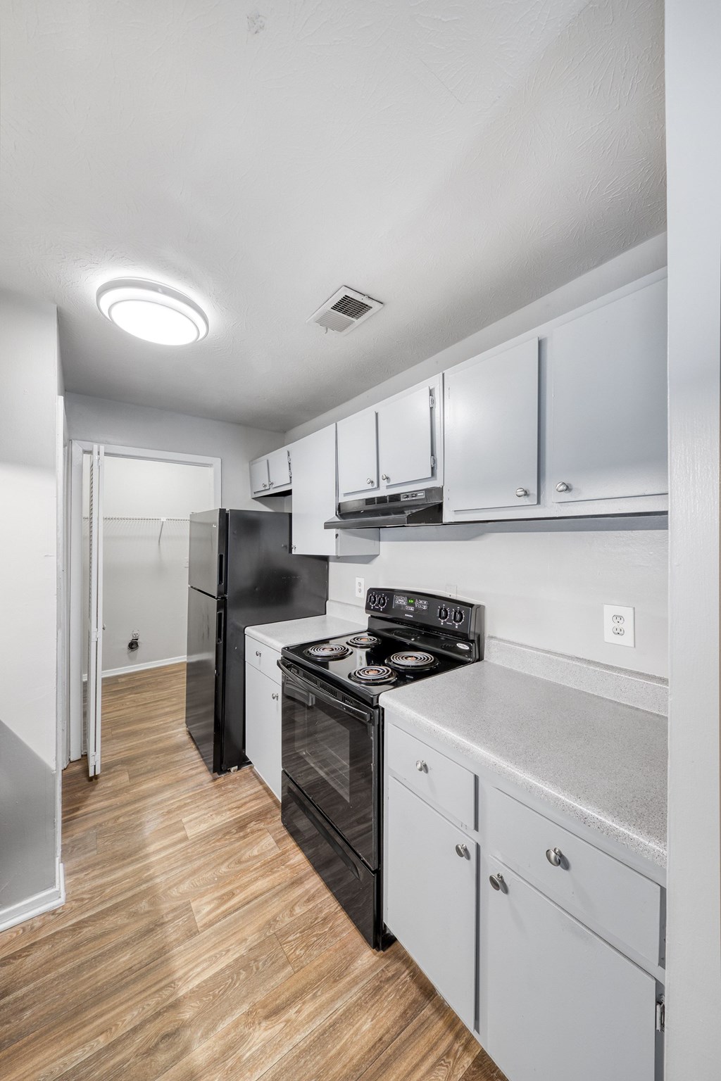 A kitchen with black appliances and white cabinets.