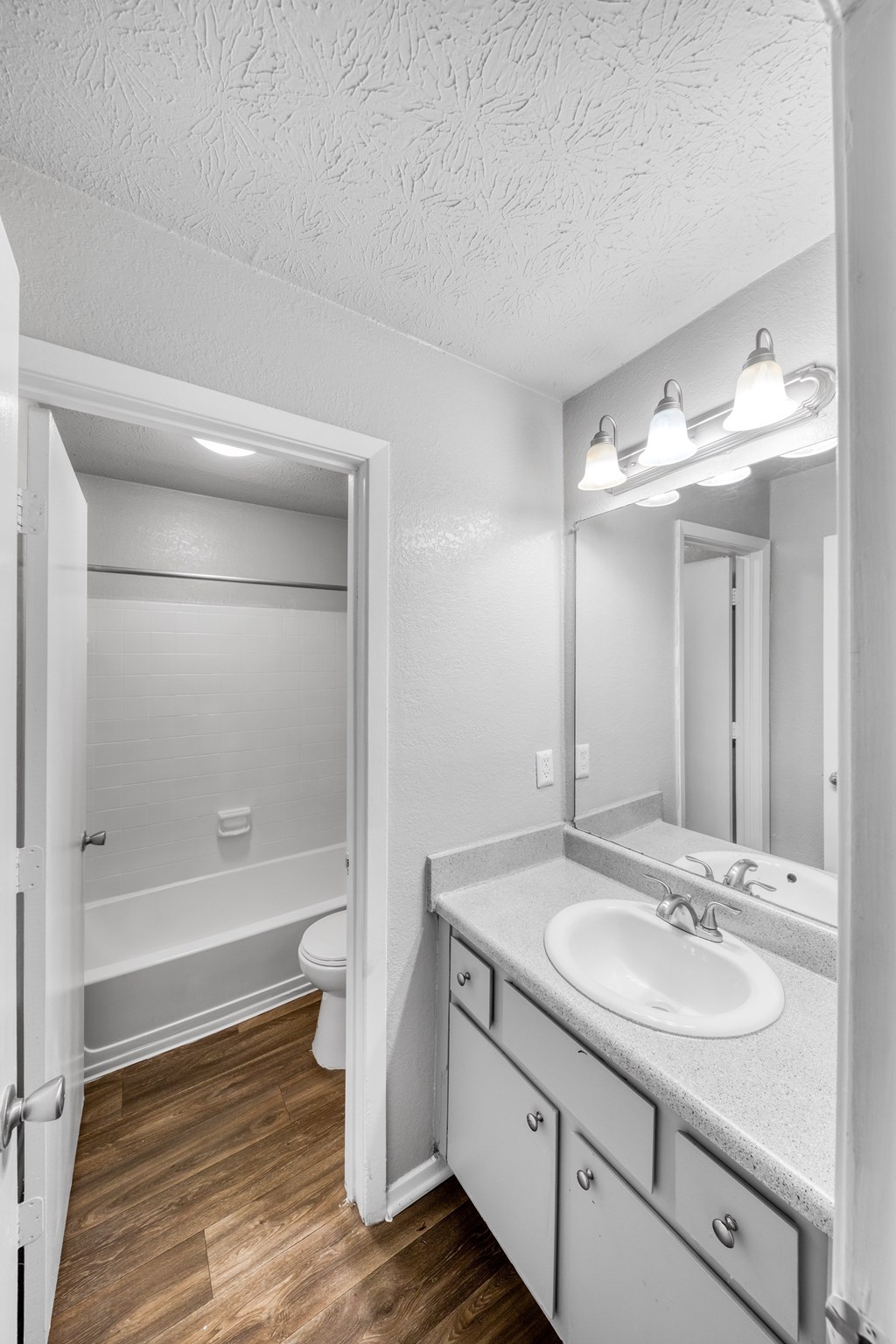 A white bathroom with a sink, mirror, and toilet.