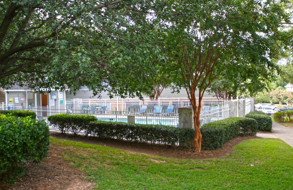 the pool is behind a fence and some trees