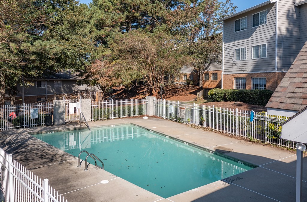 a swimming pool with a white fence and a house