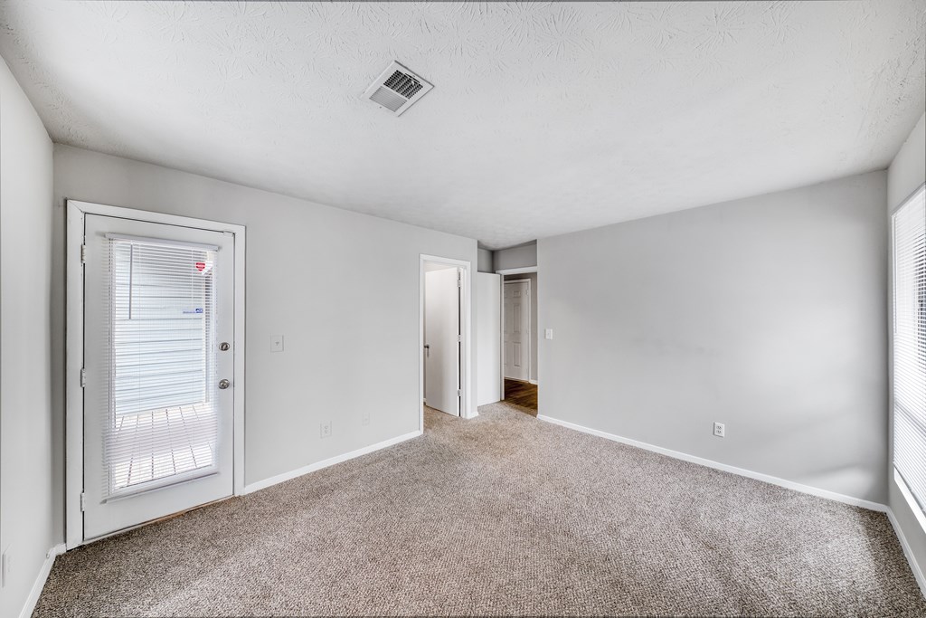 A room with a carpeted floor and a door leading to another room.