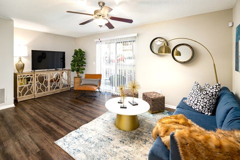 A living room with a blue couch and a gold coffee table.