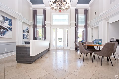 A large, elegant dining room with a chandelier, a table with chairs, and a large painting on the wall.