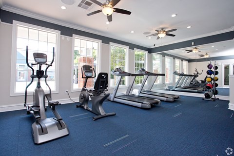 A gym with a variety of exercise equipment including treadmills, stationary bikes, and elliptical machines.