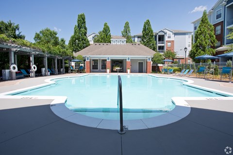 A large outdoor pool with a diving board and a building in the background.