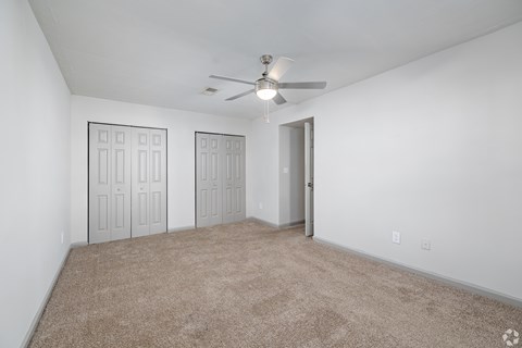 A room with a ceiling fan and carpeted floor.