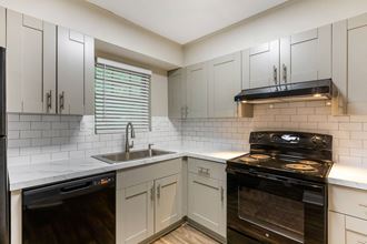 a kitchen with white cabinets and black appliances
