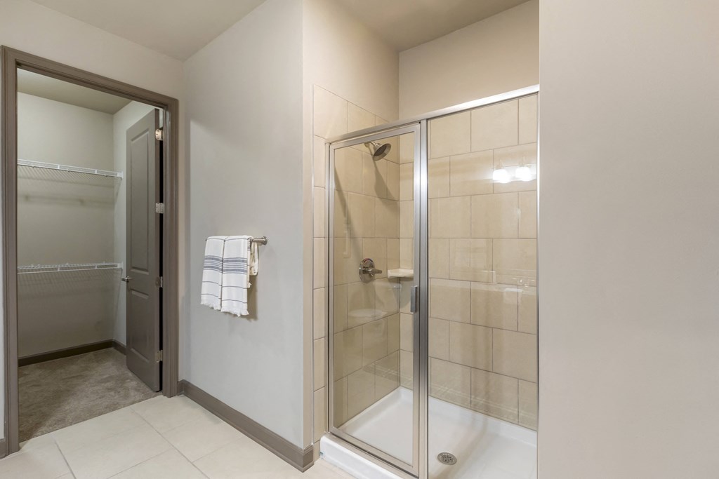 a bathroom with a glass shower stall and a white tiled floor