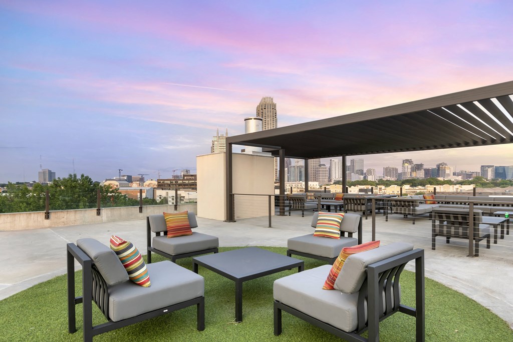 a terrace with lounge chairs and a coffee table with a city skyline in the background